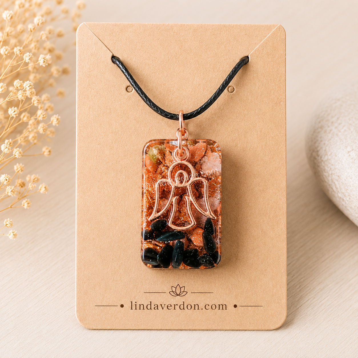 Découvrez un pendentif artisanal avec Goldstone, obsidienne noire, quartz rose et Ange en cuivre. Une création unique réalisée à la main et préparée selon une démarche vibratoire dans l'atelier Linda Verdon.