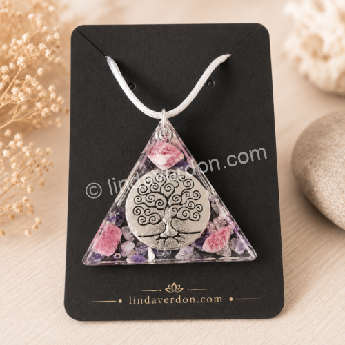 Découvrez ce Pendentif Arbre de Vie Rhodonite Améthyste, une création artisanale en résine époxy de forme triangulaire. Il associe la rhodonite, l'améthyste et le cristal de roche, sublimés par un magnifique Arbre de Vie argenté. Chaque création est préparée avec soin dans l'atelier Linda Verdon et livrée avec son cordon.