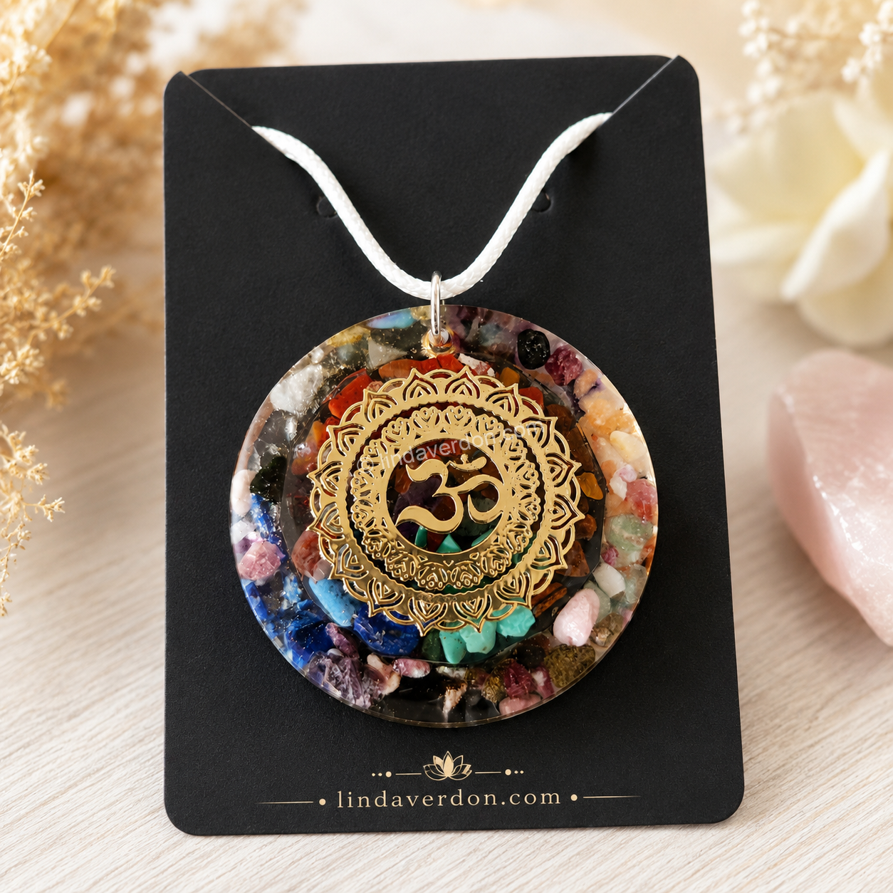 Découvrez ce Pendentif 7 Chakras OM, un médaillon artisanal réalisé en résine époxy. Il renferme les pierres naturelles représentant les 7 chakras et est sublimé par un élégant symbole OM. Chaque création est préparée avec soin dans l'atelier Linda Verdon selon notre démarche vibratoire et est livrée avec son cordon.