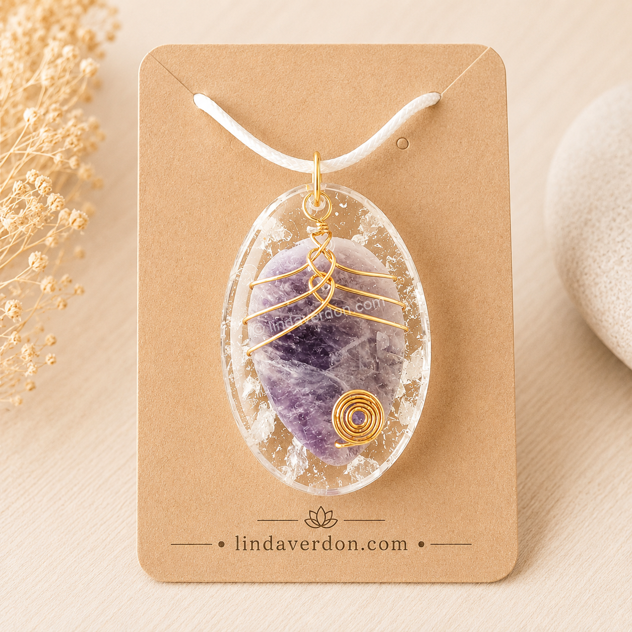Création artisanale unique en résine époxy renfermant une améthyste naturelle et un cristal de roche, délicatement enrobés d'un fil doré façonné à la main. Chaque pendentif est préparé avec soin dans notre atelier selon une démarche vibratoire inspirée des sons du bol tibétain et livré avec son cordon.
