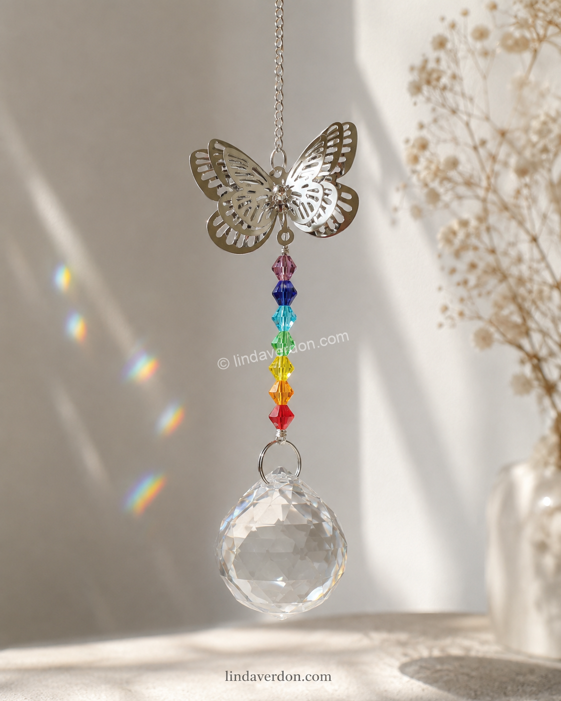 Découvrez ce capteur de lumière Papillon avec 7 chakras et boule facettée en cristal de roche, conçu pour créer de magnifiques reflets au soleil.
